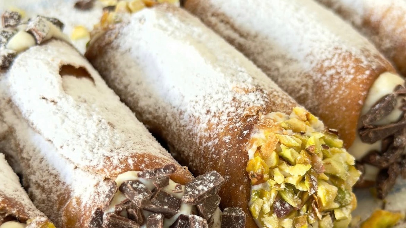 Cannoli rellenos, espolvoreados con azúcar impalpable, con pistacho y chocolate en las puntas