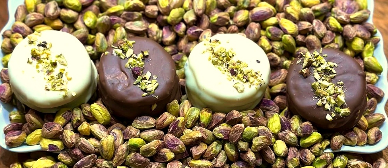 VACHOS: galletitas bañadas en chocolate blanco y negro con pistacho picado, sobre una cama de pistachos